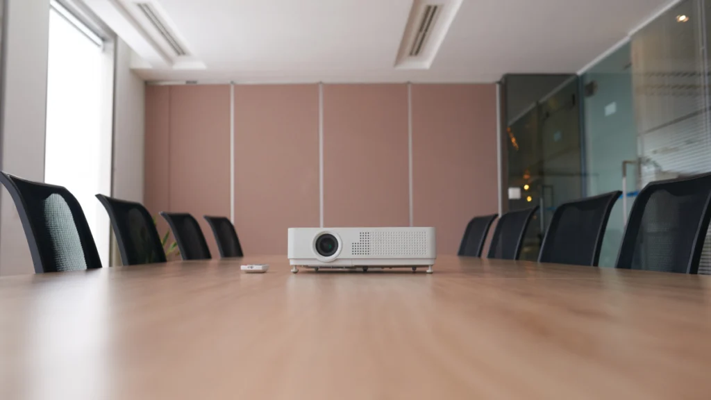 Meeting room table with projector and chairs.