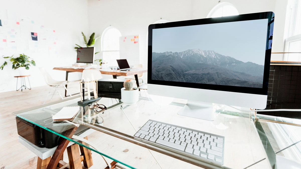 A computer screen on a desk by a window, ideal for setting up a professional AV workspace for virtual meetings.